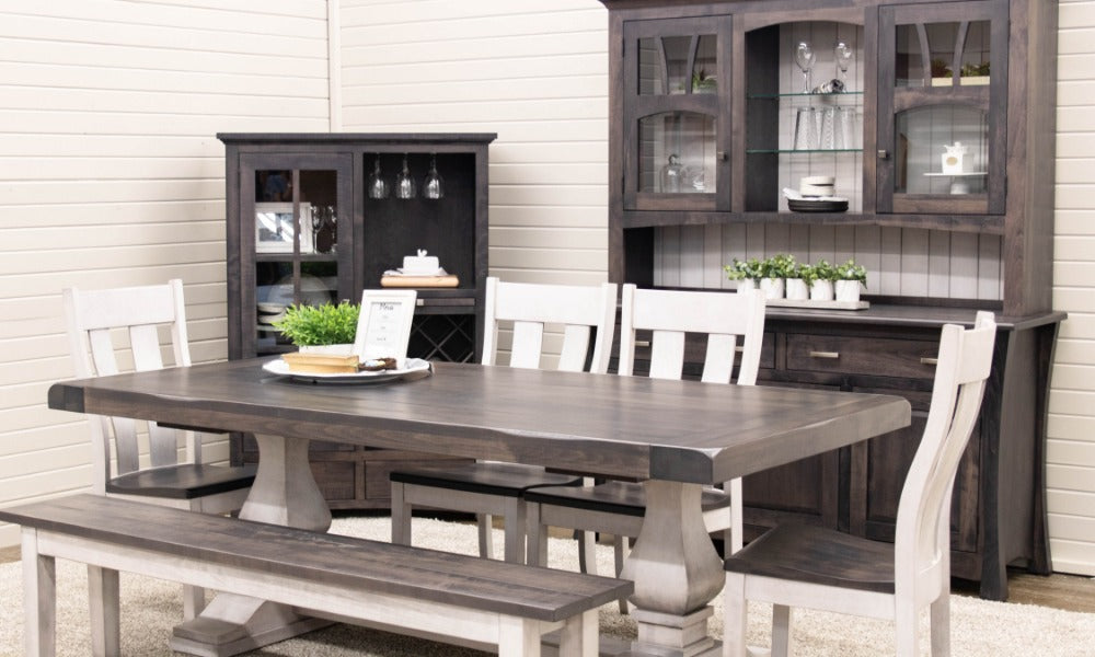 A dark wood dining table with white chairs, a matching bench, and cabinets arranged on a light area rug.