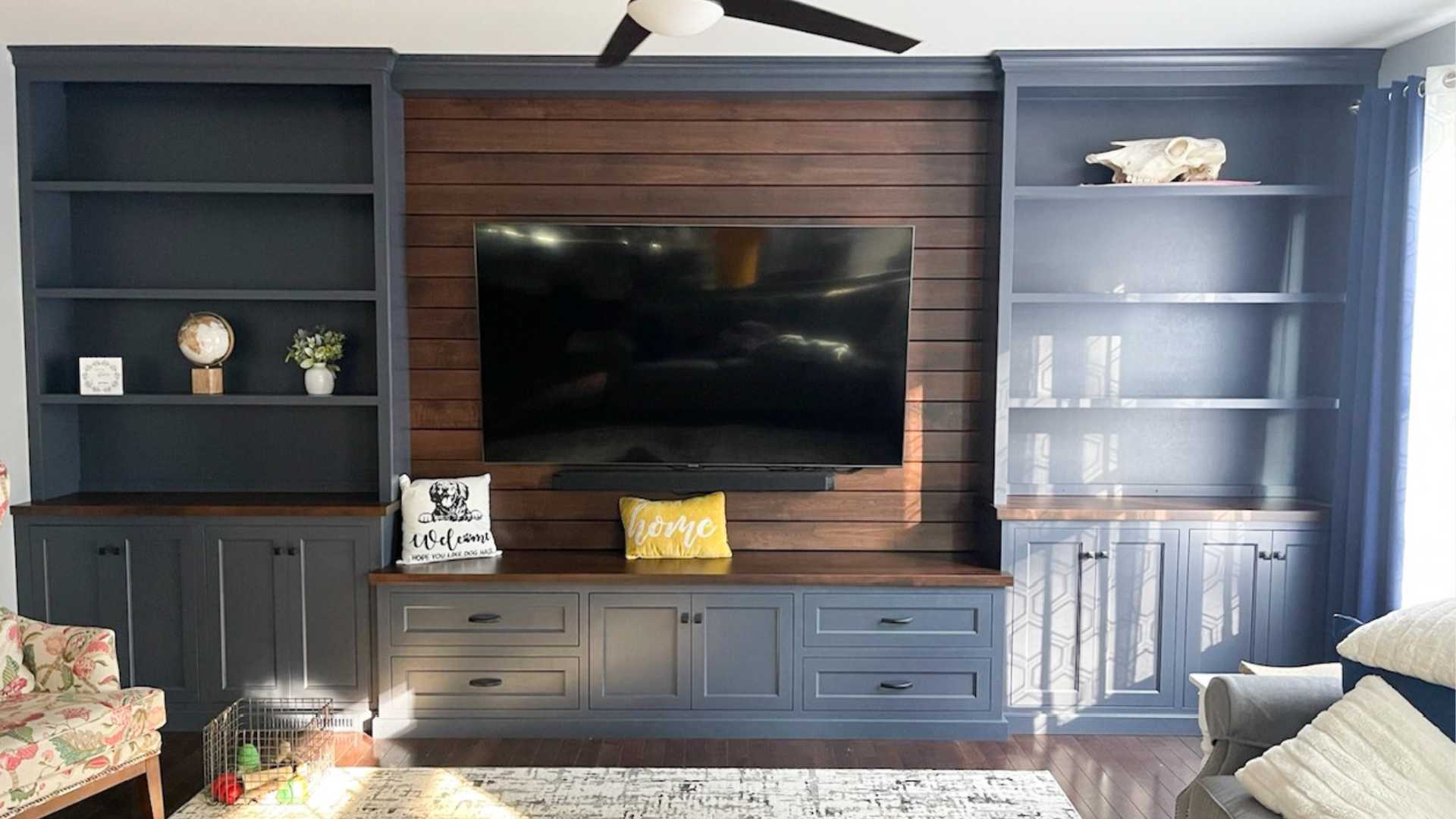 A large, wall to wall entertainment center features a navy paint on solid Maple wood.
