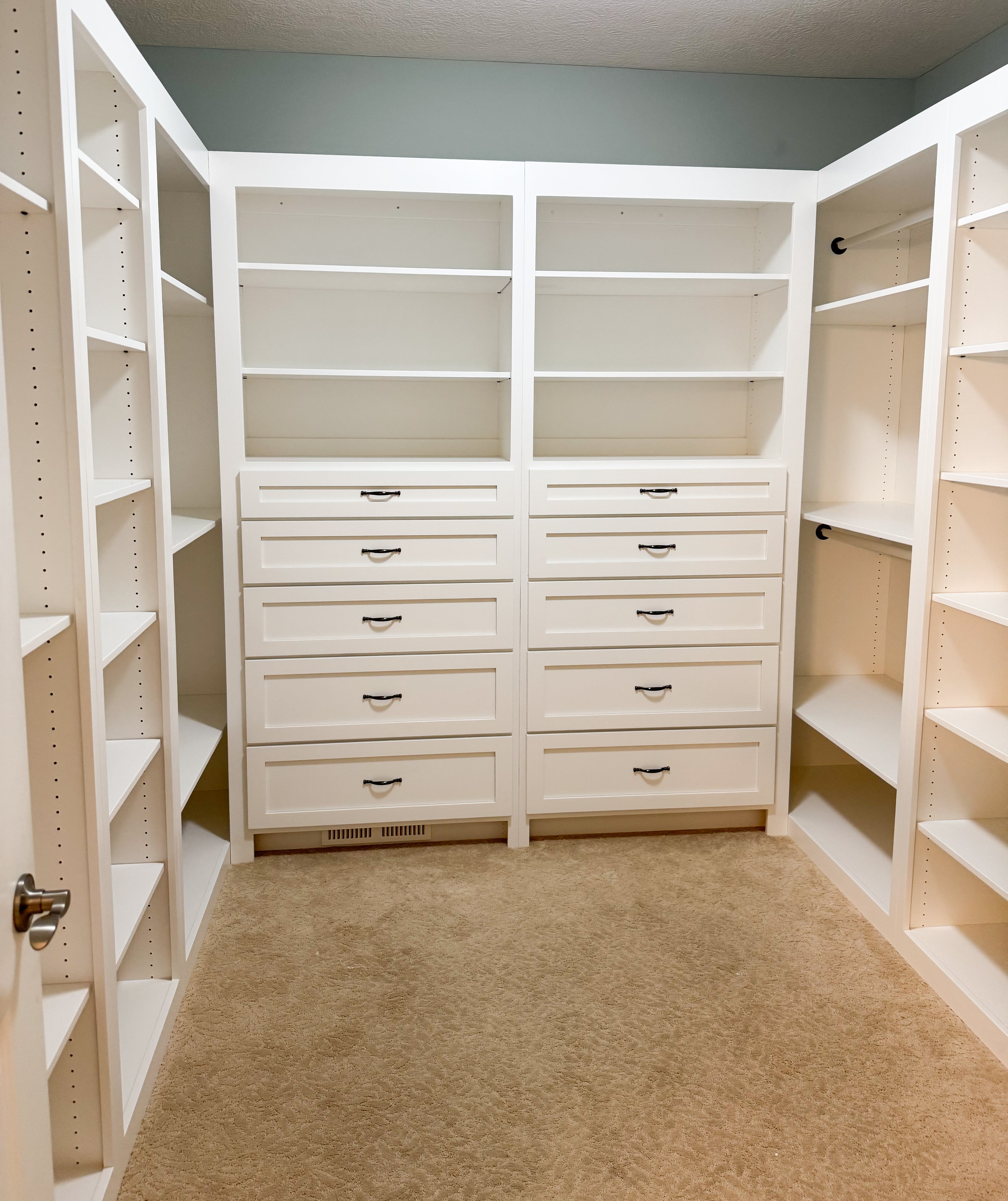 The custom wardrobe features white shelves and drawers in a clean, new style.