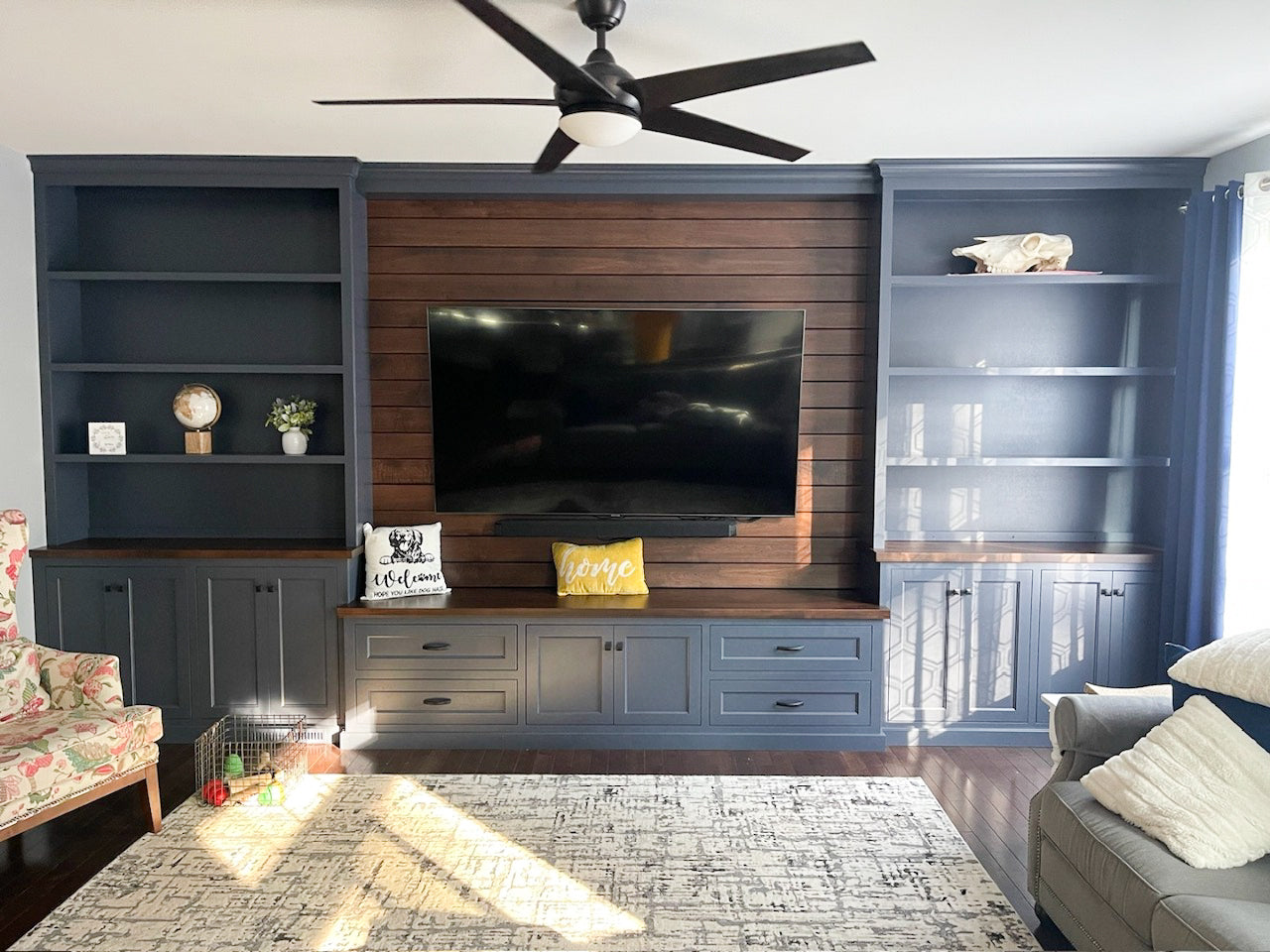 The built-in entertainment center with navy paint and warm wood tones creates a beautiful focal point in your family room.