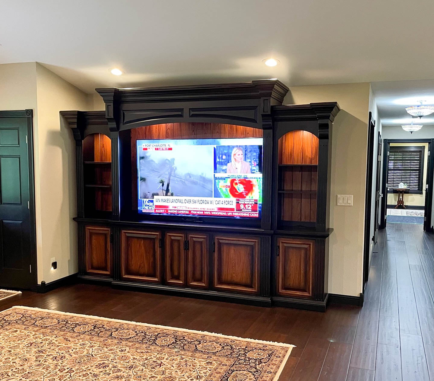 This large, black and wood custom entertainment center features detailed crown molding and custom trim work.