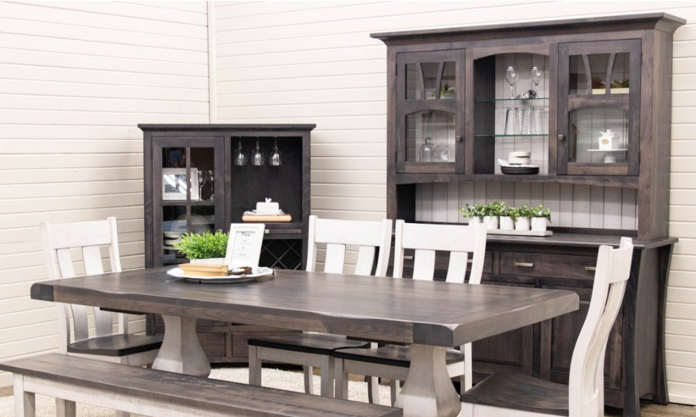 A two-tone dining table with chairs and bench seating beside a matching hutch with glass doors and shelves.
