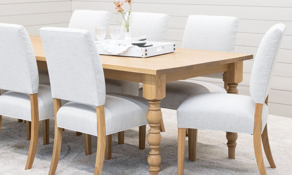 An attractive and modern wooden dining room table with six matching chairs and colorful centerpiece elements.