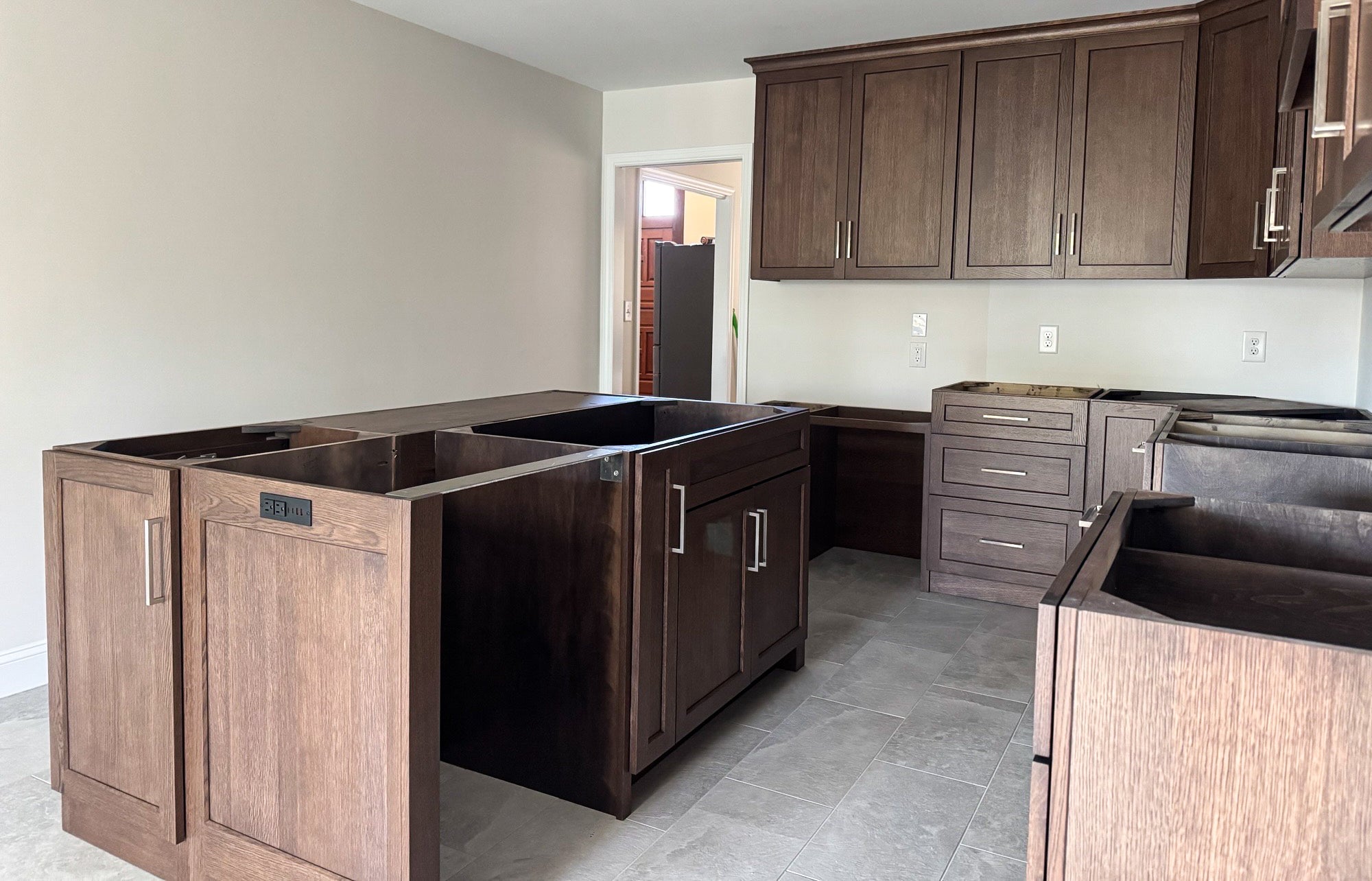 The custom kitchen shows a large island and custom wood cabinets in a warm brown tone.